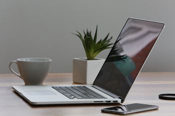 A laptop computer sitting on a desk next to a cup of coffee