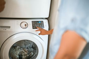 A woman points to the control panel of a washing machine