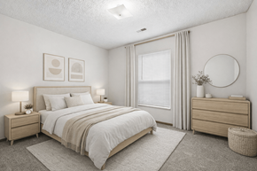 Columbus apartment for rent - A bedroom with a large bed, nightstands, and a round mirror on the wall.