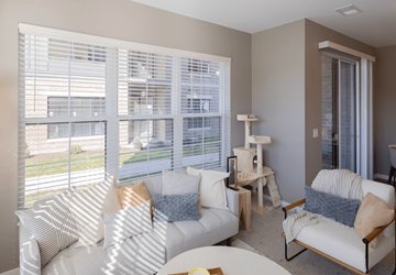 Liberty Township apartment for rent - A living room with white furniture and a large window with blinds.