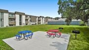 Toledo apartment for rent - a picnic area with a blue picnic table and red picnic table on a concrete patio with a