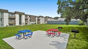 Toledo apartment for rent - a picnic area with a blue picnic table and red picnic table on a concrete patio with a