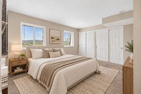 Cincinnati apartment for rent - A bedroom with a large bed and a view of the outdoors through the window.