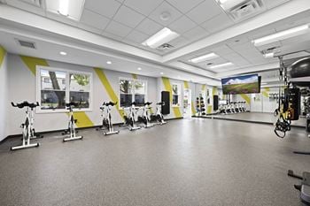 A gym with exercise bikes and a television screen.