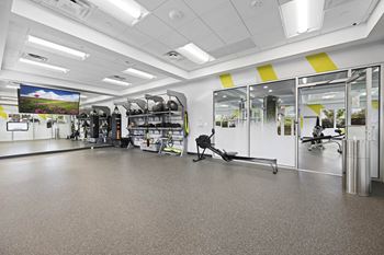A gym with a variety of equipment including treadmills, weights, and exercise machines.