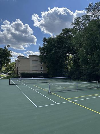 A tennis court with trees and a building in the background