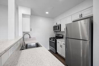 A kitchen with stainless steel appliances and white counter tops
