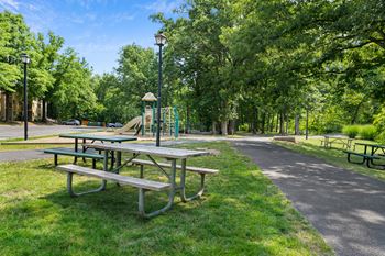 A group of picnic tables next to a playground in a park