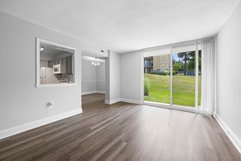 An empty living room with a large window and wood flooring