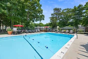 A swimming pool with chairs and umbrellas and trees