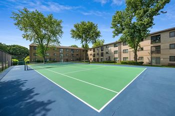 A tennis court with trees and apartments in the background