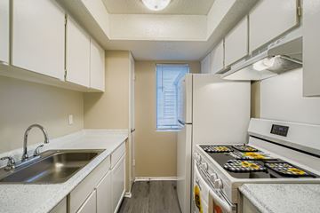Carrollton apartment for rent - A kitchen with white cabinets and a stove top oven.