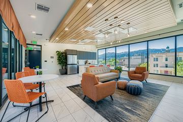 Colorado Springs apartment for rent - A modern living room with orange chairs and a wooden ceiling.