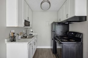 Colorado Springs apartment for rent - a kitchen with white cabinets and a black stove and refrigerator
