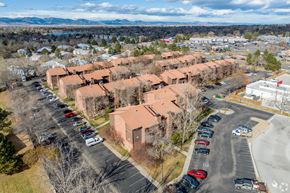 Arvada apartment for rent - A parking lot with cars and a building in the background.
