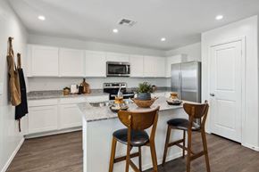 Casa Grande apartment for rent - A kitchen with white cabinets and a wooden table.
