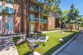 Colorado Springs apartment for rent - A sunny day at a brick apartment complex with a green lawn and trees.