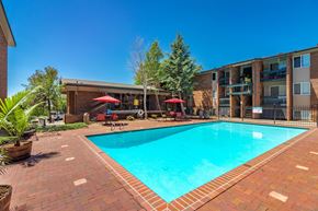 Colorado Springs apartment for rent - A swimming pool surrounded by a brick patio and a building in the background.