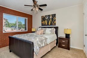 Colorado Springs apartment for rent - A bedroom with a bed, nightstand, and a painting of trees on the wall.
