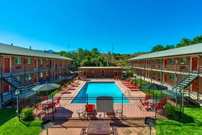 Colorado Springs apartment for rent - A pool surrounded by red chairs and umbrellas in a sunny day.