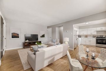 Denver apartment for rent - A modern living room with a white couch and a glass table.