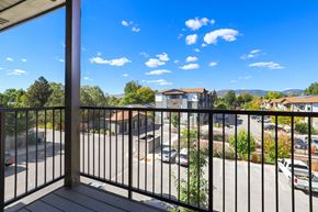 Fort Collins apartment for rent - A balcony with a black railing overlooks a parking lot and buildings.