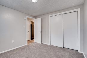 Denver apartment for rent - a bedroom with mirrored closet doors and carpeted flooring