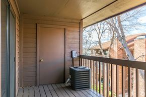 Arvada apartment for rent - A black air conditioning unit sits on a wooden deck.