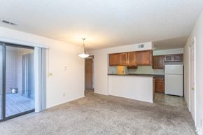 Arvada apartment for rent - A spacious living room with a kitchen area in the background.