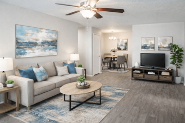 Albuquerque apartment for rent - A living room with a beige couch, a coffee table, a ceiling fan, and a painting on the wall.