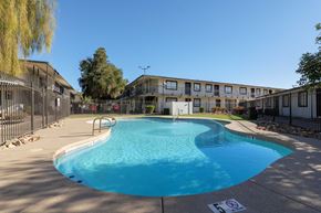 Phoenix apartment for rent - A swimming pool surrounded by a fence and buildings.
