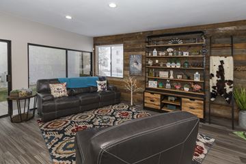 Colorado Springs apartment for rent - A living room with a black leather couch and a wooden bookshelf.