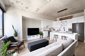 Denver apartment for rent - A modern living room with a grey sofa and a wooden chair.