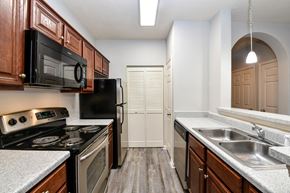 Jacksonville apartment for rent - A kitchen with dark wood cabinets and a black refrigerator.