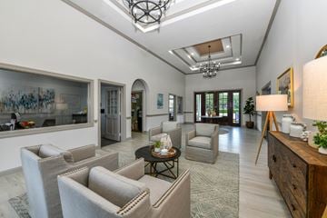 Jacksonville apartment for rent - A well-lit, spacious living room with a skylight, a grey sofa set, a wooden sideboard, and a large painting on the wall.