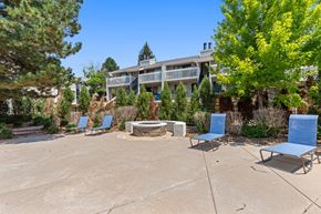 Aurora apartment for rent - a patio with blue chairs and a fire pit and a building in the background