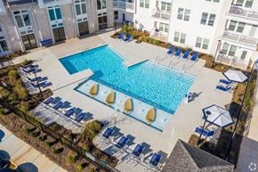 Indian Land apartment for rent - A large swimming pool surrounded by lounge chairs and umbrellas.