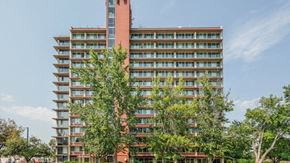 Denver apartment for rent - A tall red building with many windows and trees in front.