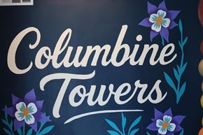Denver apartment for rent - Columbine Towers sign with flowers on a dark background.