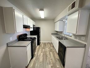 Albuquerque apartment for rent - A kitchen with white cabinets and a black refrigerator.