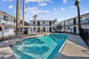 Phoenix apartment for rent - A swimming pool surrounded by palm trees and apartment buildings.