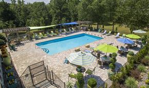 Little Rock apartment for rent - A large outdoor swimming pool surrounded by a patio area with chairs and umbrellas.
