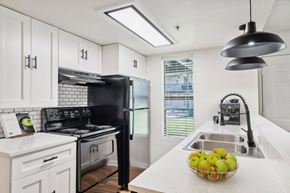 Tucson apartment for rent - A black stove and refrigerator in a kitchen with white cabinets and a bowl of apples on the counter.