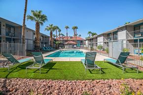 Las Vegas apartment for rent - A pool surrounded by palm trees and lawn chairs.