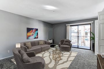 Las Vegas apartment for rent - A living room with a grey couch, a brown armchair, and a painting on the wall.