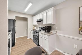 Sherwood apartment for rent - A kitchen with white cabinets and a black fridge.
