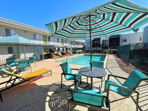 Phoenix apartment for rent - A sunny day at the pool with a striped umbrella providing shade.