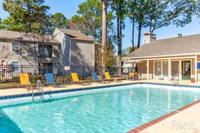 Little Rock apartment for rent - A pool with chairs and a house in the background.