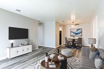 Little Rock apartment for rent - A modern living room with a grey sofa, a wooden coffee table, and a television on a white cabinet.