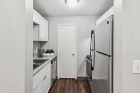 Olathe apartment for rent - A kitchen with a refrigerator, sink, and cabinets.